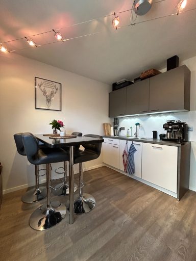 Kleine moderne Küche mit Hockern, Tisch und Pflanzen auf der Arbeitsfläche.