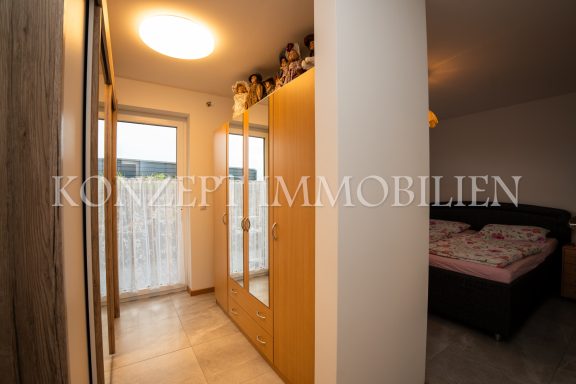 Flur mit Spiegelwand und Zugang zu einem Schlafzimmer mit Bett.