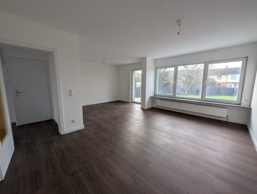 Heller, leerer Raum mit Fenster und Holzboden.