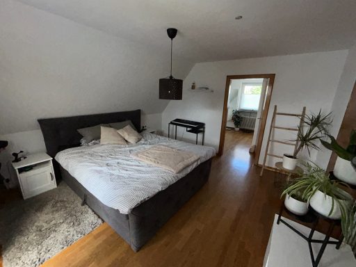 Gemütliches Schlafzimmer mit Doppelbett, Tisch und Pflanzen, hell und modern eingerichtet.