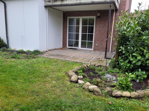 Eingangsbereich mit gepflastertem Weg, Garten und angrenzendem Pflanzenbeet.