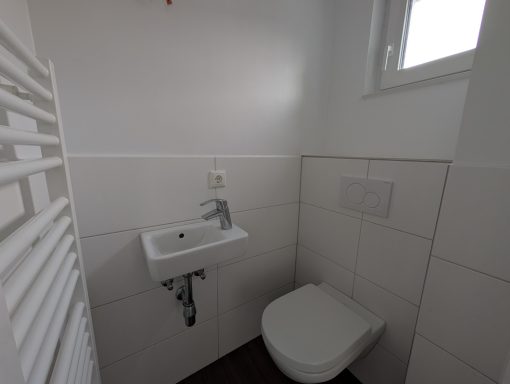 Kleines, modernes Badezimmer mit Toilette und Waschbecken an der Wand.