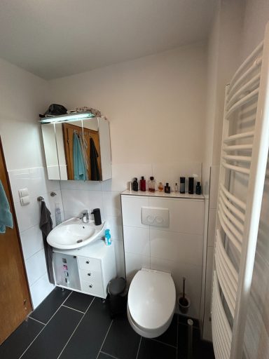 Kleines Badezimmer mit Toilette, Waschbecken und dekorativen Pflegeprodukten.