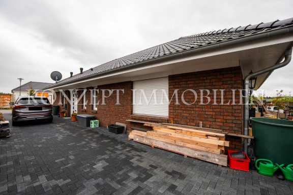 Haus mit Ziegelfassade, Flachdach und Parkplatz im Vordergrund.