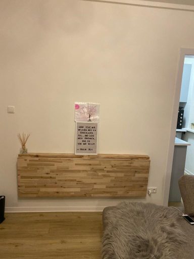 Holzregal an einer Wand mit einer Notiz darüber und einem weichen Teppich davor.