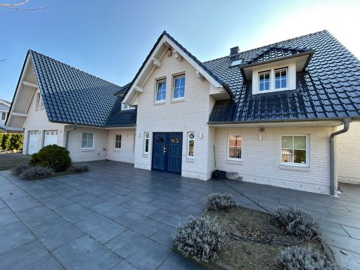 Modernes Einfamilienhaus mit hellen Fassaden und einer blauen Eingangstür.