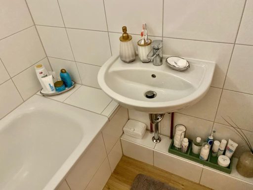 Badezimmer mit Waschbecken, Badewanne und verschiedenen Pflegeprodukten auf einem Regal.