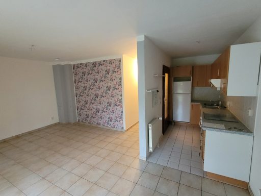 Heller offener Wohnbereich mit Küche und blühendem Tapetenmuster an einer Wand.