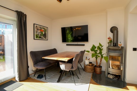 Gemütliche Essgruppe mit Tisch, Stühlen und Fernseher in einem hellen Raum.