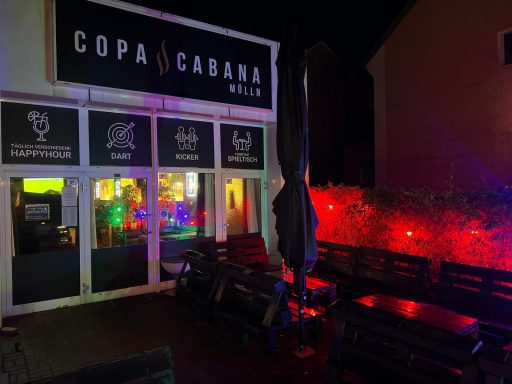 Nachtaufnahmen eines Restaurants mit bunten Lichtern und Außenterrasse.