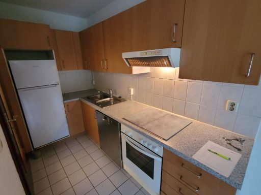 Kleine moderne Küche mit Holzschränken, Herd, Spülbecken und Kühlschrank.