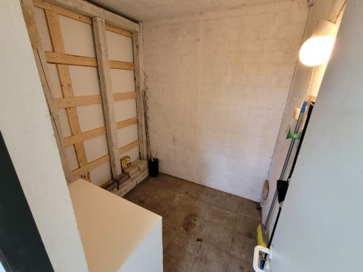 Leerer Raum mit Betonboden, unvollendeten Wänden und schwachem Licht.